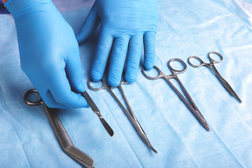 Detail shot of sterilized surgery instruments with a hand grabbing a tool ,