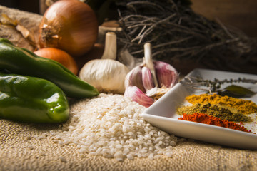 Still life with the ingredients to make a rice stew with vegetables and spices.
