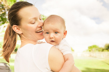 Mother holding baby boy outdoors. Happy family lifestyle. 
