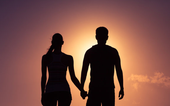 Silhouetted of man and woman holding hands. Love and relationships concept. 
