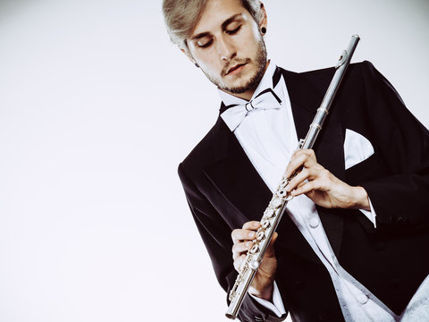 Male flutist wearing tailcoat holds flute