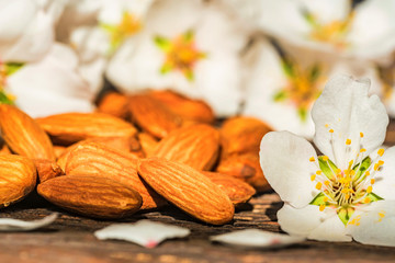 Almonds and white flowers on dark wooden surface