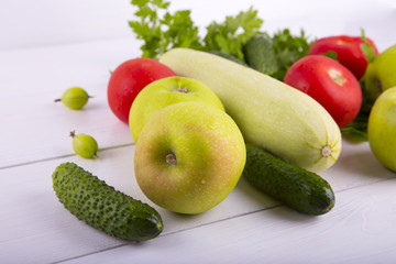Closeup different vegetables, fruits and greens on white wooden table
