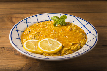 Plate of chicken rice with vegetables and spices presented on a wooden table.