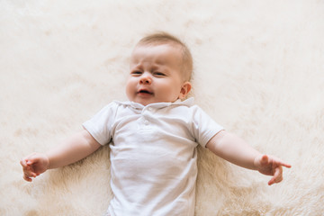 Fototapeta premium Little beautiful infant baby crying and laying on white background isolated