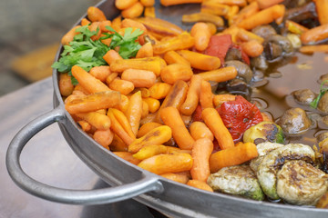 Carrot baby, mushrooms and other vegetables baked in a large frying pan