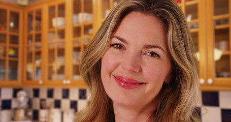 Close up of middle aged Caucasian woman laughing at camera inside kitchen