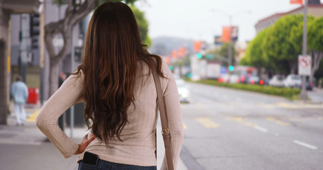 Latina woman standing on busy urban street waiting impatiently for ride