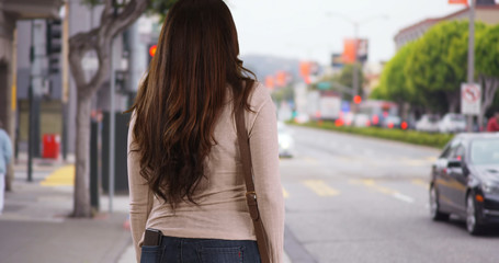 Latina woman standing on busy urban street waiting impatiently for ride