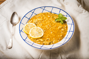 Plate of chicken rice with vegetables and spices presented on a white cloth