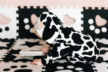 Portrait of a charming cute baby. A boy in a black and white suit sits and watches a book in the house