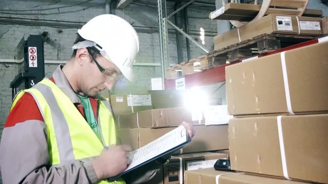 Portrait warehouse worker in protective gear makes notes