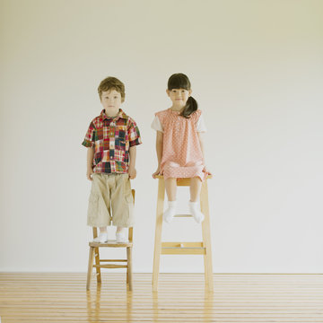椅子の上に立つハーフの男の子と日本人の女の子