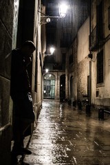 Silhouette of a man standing on the street at gothic quarter in Barcelona at rainy night, depression loneliness and sadness