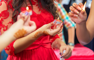 She holds the candle in his hand Henna party . Hands and fingers are drawn to henna . Female hand with henna tattoo .