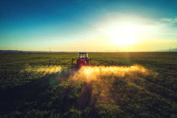 Obraz premium Aerial view of farming tractor plowing and spraying on field