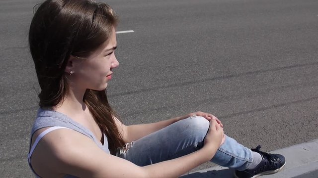 Closeup of cute caucasian teen girl on a city background. Looks into the distance. Static camera.