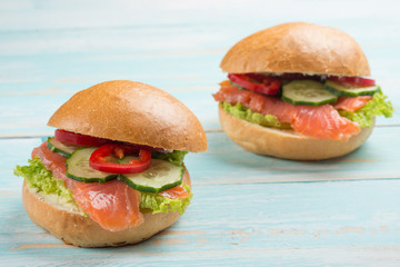 Sandwich with red fish and vegetables, on a blue wooden background. Concept of healthy food, diet.