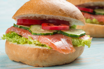 Sandwich with red fish and vegetables, on a blue wooden background. Concept of healthy food, diet.
