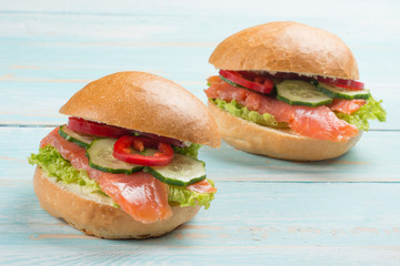 Sandwich with red fish and vegetables, on a blue wooden background.