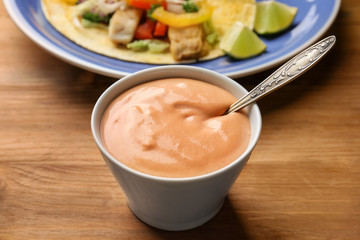 Tasty creamy sauce for fish taco in bowl on wooden table