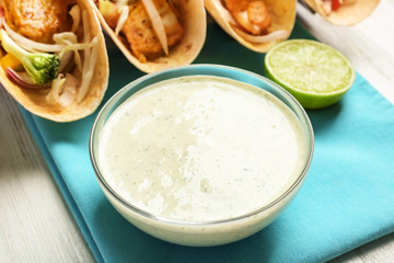 Tasty creamy lime sauce for fish taco in bowl on wooden table