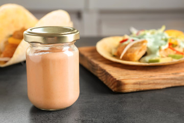 Tasty creamy sauce for fish taco in glass jar on kitchen table