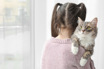 Cute little girl with cat near window at home © New Africa