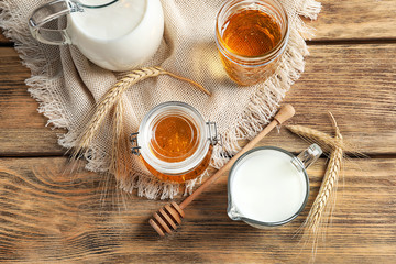 Beautiful composition with milk and honey on wooden background