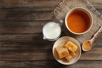 Composition with milk and honey on wooden background, top view