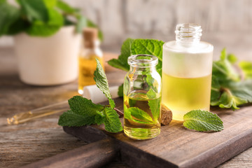 Bottles of essential oil and mint leaves on table