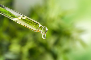 Dropper with essential oil on blurred background