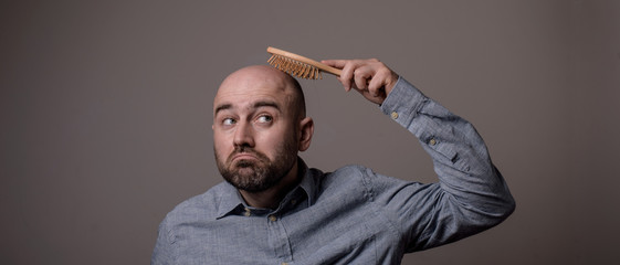 confused bald man with hair brush
