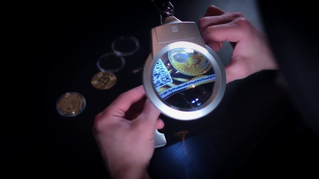 4K Man Investigating a Bitcoin Wallet under Magnifying Glass