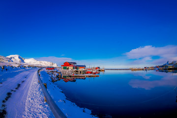 Outdoor view of harbour area with fishing wooden buildings behind viewed from the road, covered with snow in Svolvaer