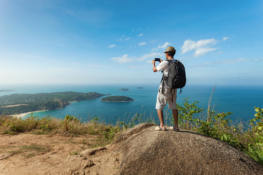 travel man with backpack standing take a photo with smartphone and see beautiful scenery landscape nature view on rock mountain in phuket thailand.