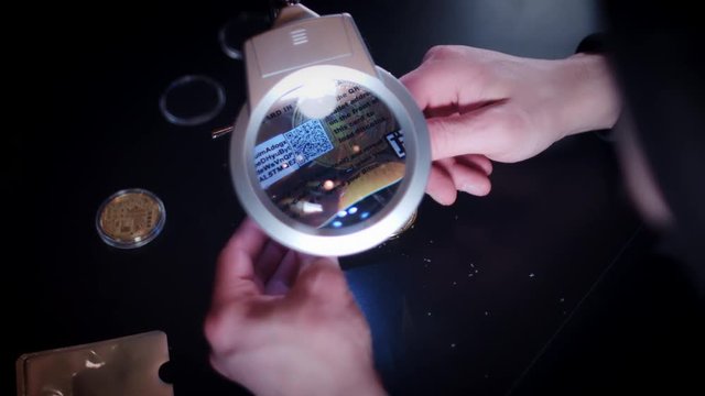 4K Man Investigating a Bitcoin Wallet under Magnifying Glass