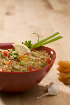 quinoa salad with vegetables in red bowl
