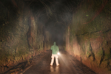 Man with a flashlight exploring in the dark forest