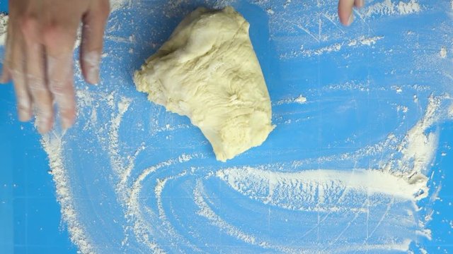 Slow motion footage. Baker hand kneading dough. Top view