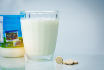 Sweetened flavored milk tablets and one glass of milk and milk bottle on white background. Calcium food products from cow milk for healthy bone.
