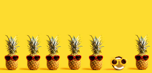 Series of pineapples and a coconut wearing sunglasses on a yellow background