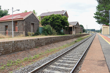 Fototapeta na wymiar train tracks and a bluestone railway station buildings and platform