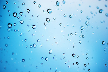 Drops of rain on glass with blue background