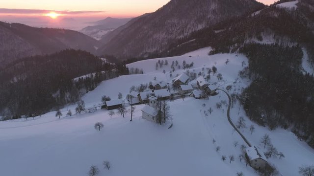 Colorful aerial sunrise in Lepena Valley flying over the snow covered landscape in Slovenia.
