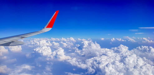 Fototapeta na wymiar Right wing of jet plane over cloudy sky