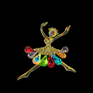 isolated golden brooch on a black background in the shape of a ballerina, dancer