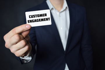 Businessman shows business card with the inscription:CUSTOMER ENGAGEMENT