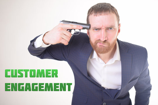 The businessman holds a gun in his hand and shows the inscription:CUSTOMER ENGAGEMENT