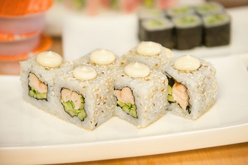 Rolls with smoked chicken and cucumber on a white plate in the interiors of the cafe. Japanese food.